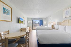 Habitación de hotel con 2 camas y mesa en SeaMist Driftwood Vacation Studio with Balcony, en Myrtle Beach