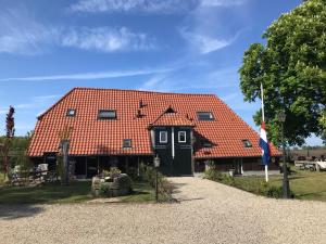 een huis met een rood dak en een vlag bij Een mooie plek in Markelo