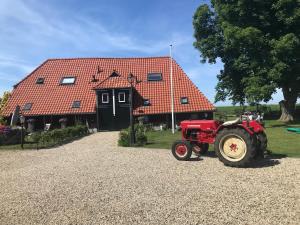 un tractor rojo estacionado frente a un edificio en Een mooie plek en Markelo