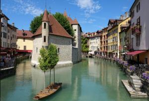 ein Fluss mit zwei Booten in einer Stadt mit Gebäuden in der Unterkunft 15 Rhône beau T2 avec parking gratuit in Annecy
