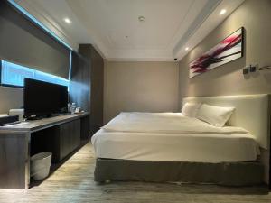 a bedroom with a bed and a flat screen tv at Royal Fine Hotel in Kaohsiung