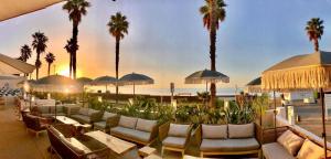 a resort patio with tables and chairs and palm trees at Le Rose Thé in La Ciotat