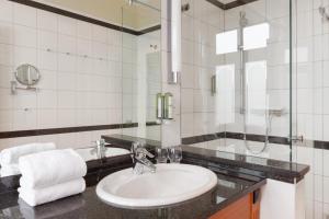 a white bathroom with a sink and a mirror at Vju Hotel Rügen in Göhren