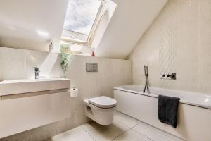 y baño con aseo, lavabo y tragaluz. en Cliff Top Heights-Beach front house near Brighton en Rottingdean