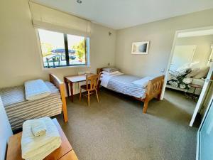 聖阿諾的住宿－The bach，一间卧室设有两张床、一张桌子和一个窗口
