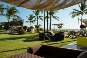 a resort with palm trees and a lawn with chairs and umbrellas at Holiday Inn Express Baruna, an IHG Hotel in Kuta