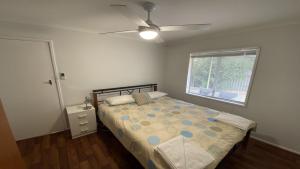 Un dormitorio con una cama y un ventilador de techo. en Frangipani Cottage, en Jurien Bay