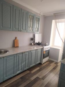 a kitchen with blue cabinets and a sink and a stove at Avtovokzal 3 Room apt in Qyzylorda