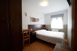 a bedroom with a bed and a desk and a window at Pensión Serafín in Avilés