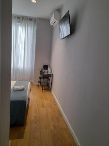 Habitación con cama y TV en la pared. en Marina Rooms, en Madrid