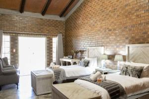 1 dormitorio con 2 camas y pared de ladrillo en Kwadiwa Ranch en Baines Drift