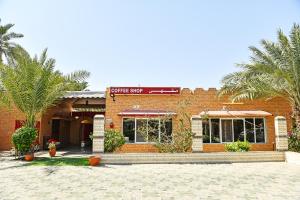 a brick building with palm trees in front of it at OYO 138 Gulf Sand Motel in Barka