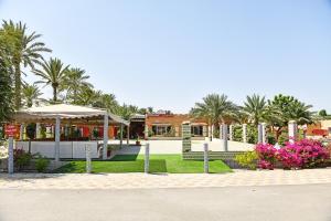 a park with trees and flowers and a building at OYO 138 Gulf Sand Motel in Barka
