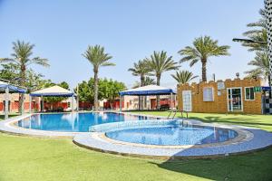 a large swimming pool in a yard with palm trees at OYO 138 Gulf Sand Motel in Barka