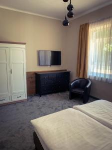 a bedroom with a bed and a tv and a chair at Garda Hotel in Szombathely