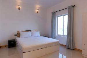 a white bedroom with a bed and a window at Splendour Grand in Maalhos