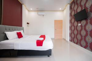 a bedroom with a bed with a red chair on it at RedDoorz Syariah near Minangkabau International Aiport in Duku