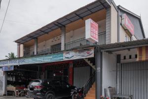 a black car parked in front of a store at RedDoorz Syariah near Minangkabau International Aiport in Duku