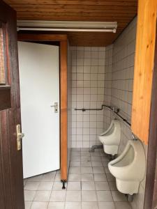 a bathroom with three urinals and a door and two toilets at Zeltplatz Großer Wald in Gaggenau