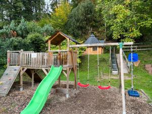 a playground with a green slide and a house at Zeltplatz Großer Wald in Gaggenau