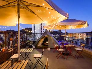 a patio with tables and chairs and a tent at Mange Tak Resort Onomichi in Onomichi