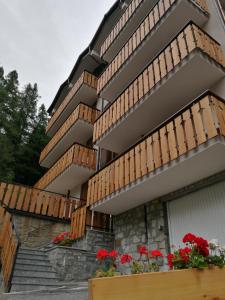 un edificio con balcones de madera y flores rojas. en Cogne come una volta, en Cogne