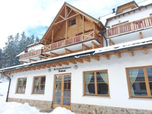 ein Haus im Winter mit Schnee auf dem Boden in der Unterkunft Pohorje Village Wellbeing Resort - Wellness & Spa Hotel Bolfenk in Hočko Pohorje