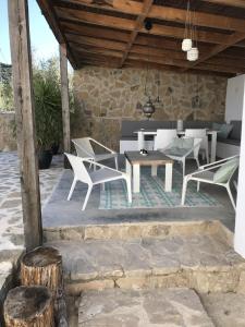 un patio con sillas blancas y una mesa en Casa Olivo en Iznájar