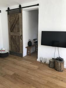 sala de estar con puerta corredera de granero y TV de pantalla plana en Casa Olivo en Iznájar