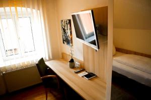 een kamer met een bureau, een televisie en een bed bij Weinstube Sinas Brettl in Nördlingen
