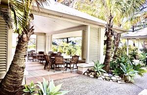 eine Terrasse mit einem Tisch, Stühlen und Palmen in der Unterkunft Spacious & Magnificent Views Apartment in Gold Coast
