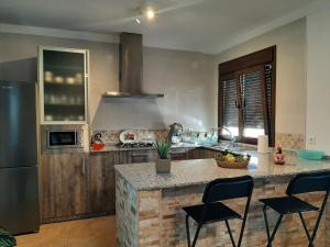 een keuken met een aanrecht met stoelen en een koelkast bij Vivienda Rural Villa Madrid Alcázar in El Gastor