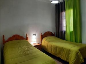twee bedden in een kamer met groene gordijnen bij Vivienda Rural Villa Madrid Alcázar in El Gastor +15 foto's
