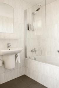 a white bathroom with a shower and a sink at Hotel Restaurant Belvédère in Schoonhoven