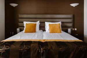 a large bed with two orange pillows on it at Hotel Restaurant Belvédère in Schoonhoven