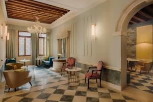 a lobby with tables and chairs and a chandelier at NH Venezia Santa Lucia in Venice