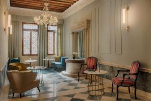 a lobby with tables and chairs and a chandelier at NH Venezia Santa Lucia in Venice