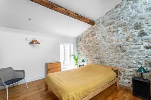 Un dormitorio con una pared de piedra y una cama en Singulary House-Loft with AC Downtown - Dodo et Tartine, en Hyères
