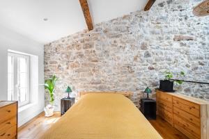 Cama en habitación con pared de piedra en Singulary House-Loft with AC Downtown - Dodo et Tartine, en Hyères