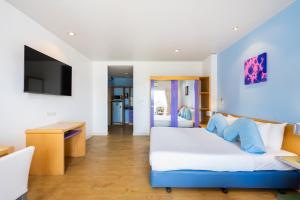 a bedroom with a blue and white bed and a tv at Best Bella Pattaya in North Pattaya