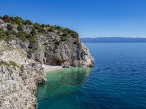 a cliff with a beach next to the water at Apartment Rea with Pool in Brseč