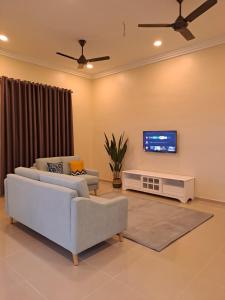sala de estar con 2 sofás y TV de pantalla plana en ZN Homestay Gong Badak en Kampong Pengkalan Maras