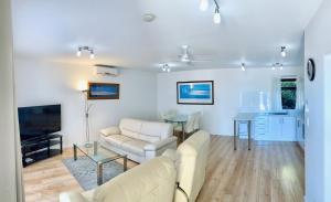 a living room with a couch and a tv and a table at Atlantic West Beach Apartments in Adelaide