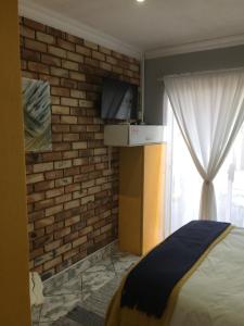 a bedroom with a brick wall and a bed and a television at B&B 464 on 22nd Ave in Pretoria