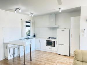 a white kitchen with a table and a refrigerator at Atlantic West Beach Apartments in Adelaide