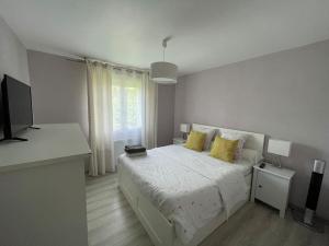 biała sypialnia z łóżkiem z żółtymi poduszkami w obiekcie Maison tout confort en Touraine 4 chambres w mieście Fondettes