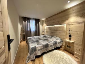 um quarto com uma cama e uma parede de madeira em OURS POLAIRE bel appartement village et pistes em La Clusaz