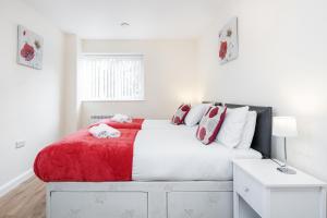 a white bedroom with a large bed with a red blanket at MPL Apartments - Queens Broadway F4 in Watford