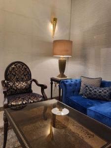 Ambassador, a Boutique Hotel في عمّان: غرفة معيشة مع أريكة زرقاء وكرسي