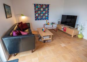 a living room with a black leather couch and a tv at Marna Guesthouse doubleroom nr.2 in Tórshavn